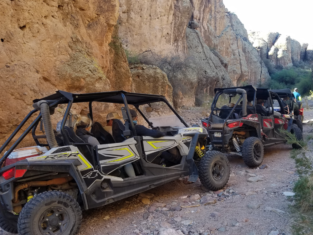 Two side-by-side UTVs crawling across the rugged desert terrain